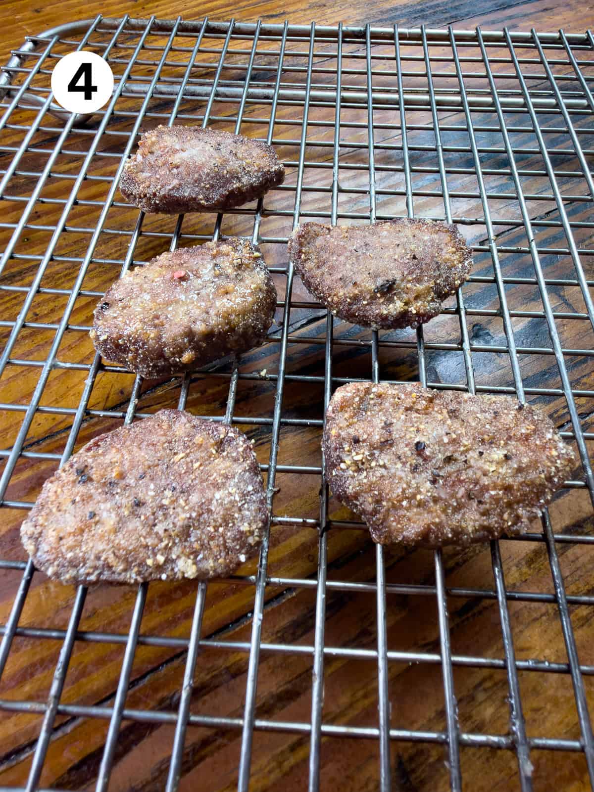 Draining backstrap on a wire rack sitting on a wooden table.