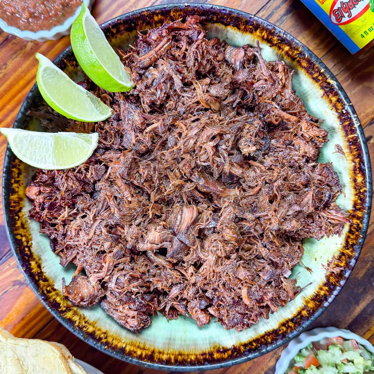 Venison barbacoa recipe in a bowl with limes