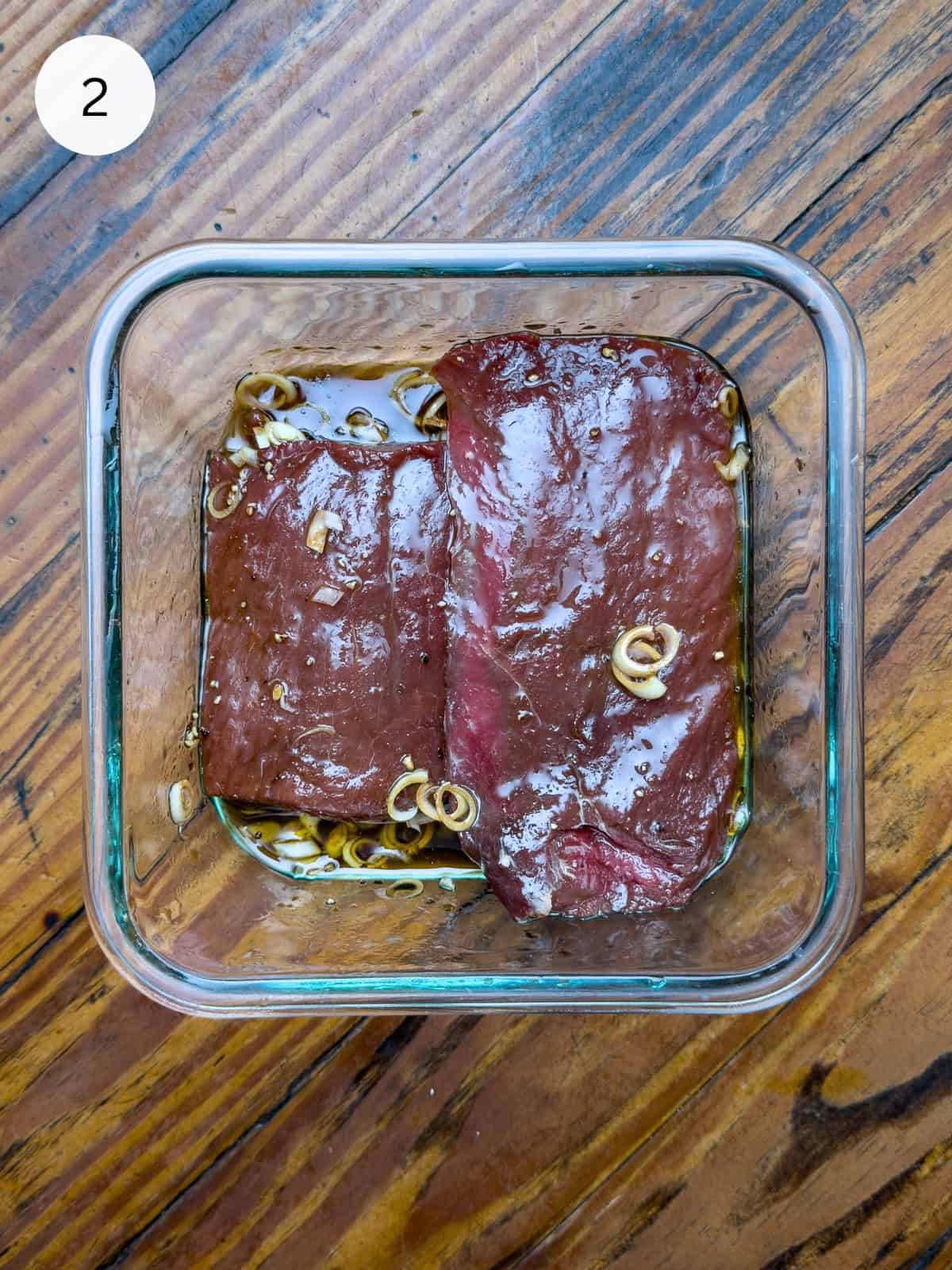 Steaks marinating in a bowl.