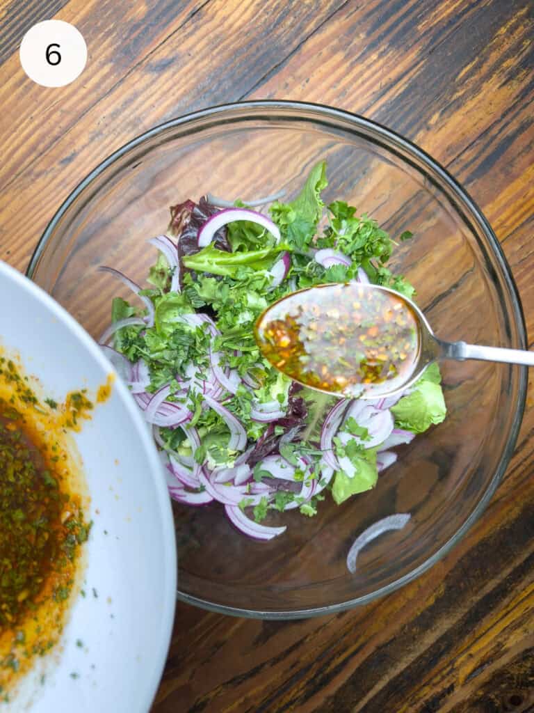 Thai salad in a bowl with dressing being poured over it.