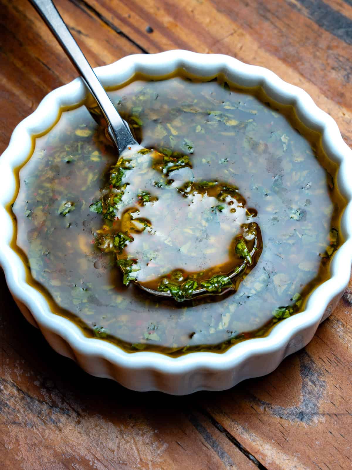 Basil chimichurri in a white bowl with a spoon.