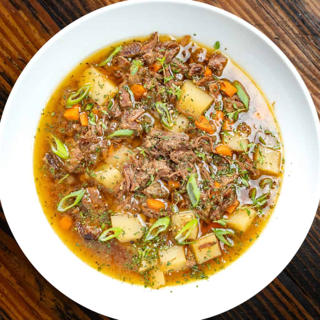 Venison stew in a white bowl on a wooden table