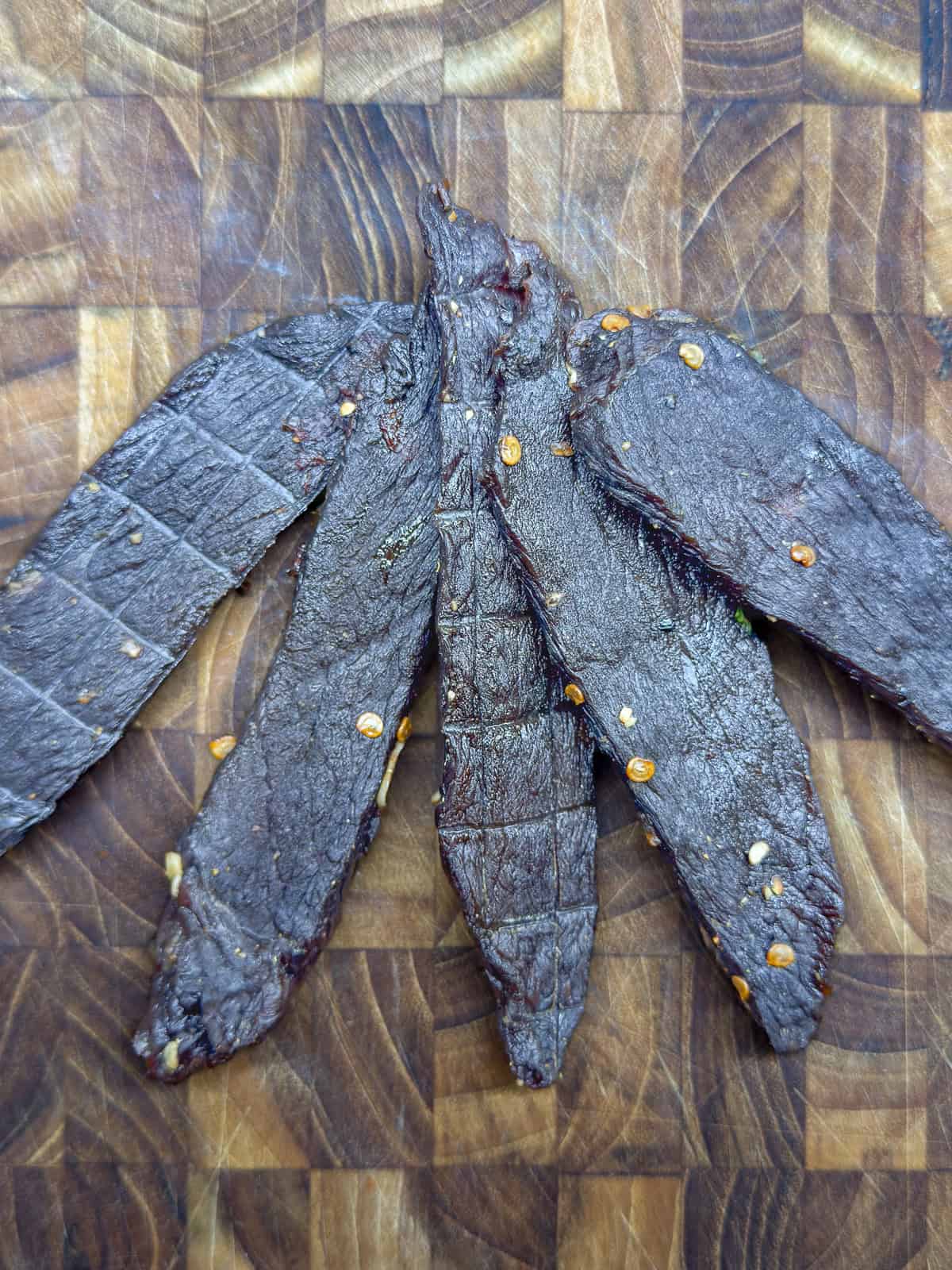 Venison jerky on a wooden cutting board.