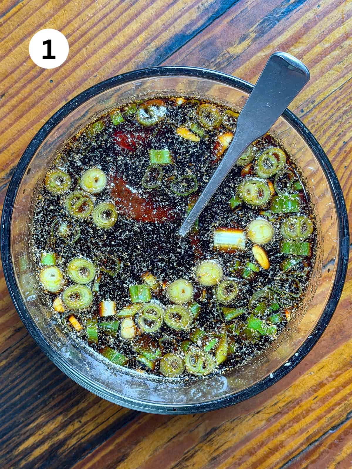 Venison jerky marinade in a bowl on a wooden table.