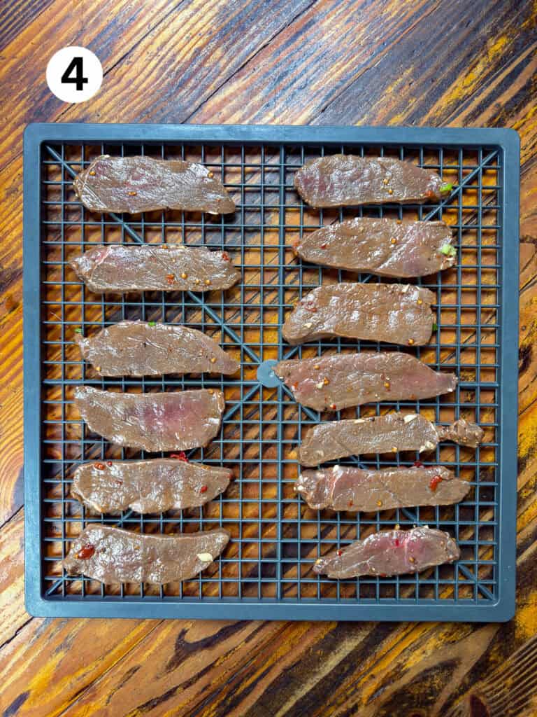 Venison on a gray dehydrator rack.