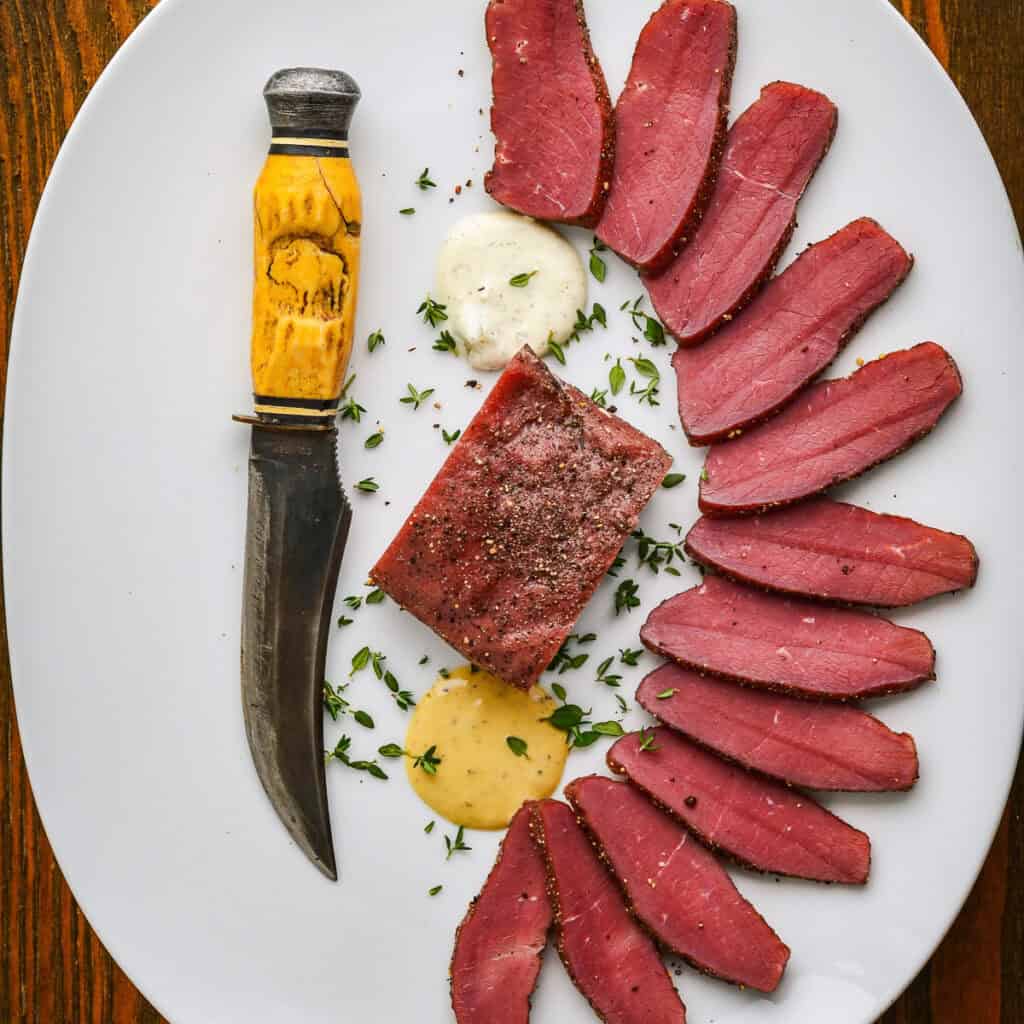 Smoked backstrap recipe on a white plate with a knife.