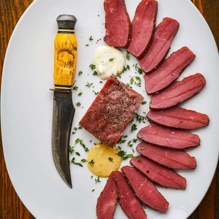 Smoked backstrap recipe on a white plate with a knife.