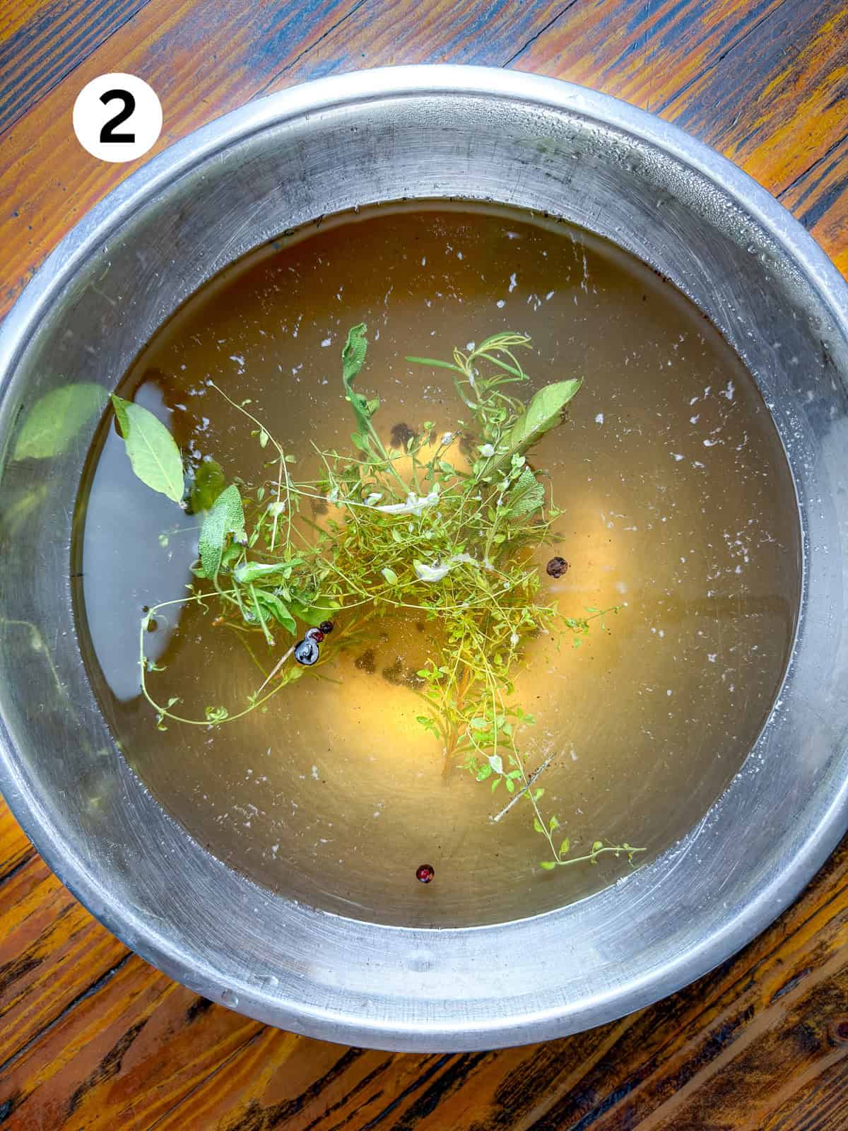 Smoked venison backstrap brine in a pot on a wooden table.