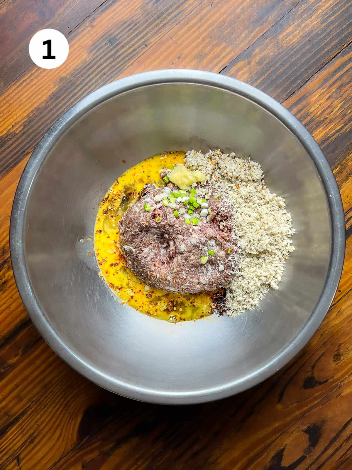 Unmixed venison meatball ingredients in a wooden bowl.