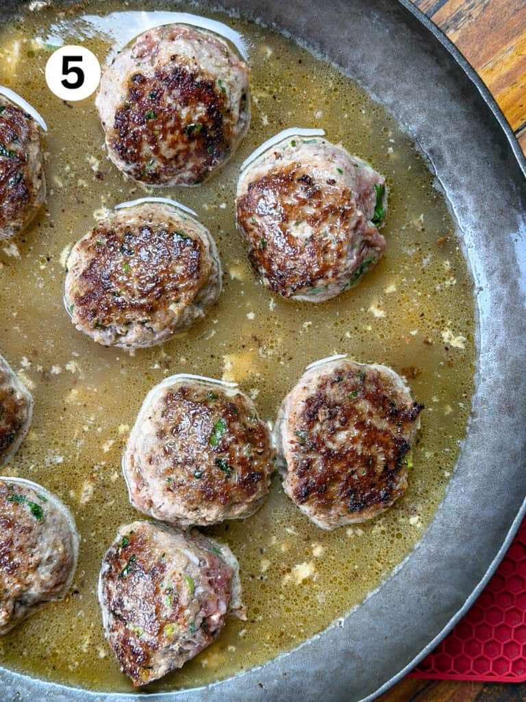 Venison meatballs in a pan with stock.