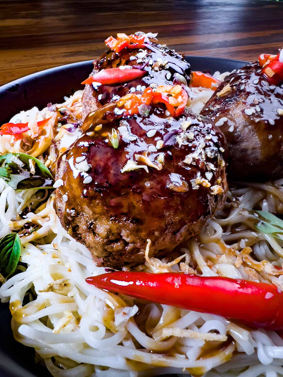 Venison meatballs on a black plate with noodles.