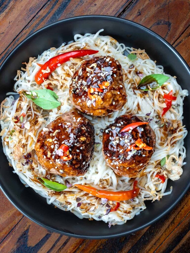 A plate of venison meatballs recipe over rice and garnished with peppers and herbs.