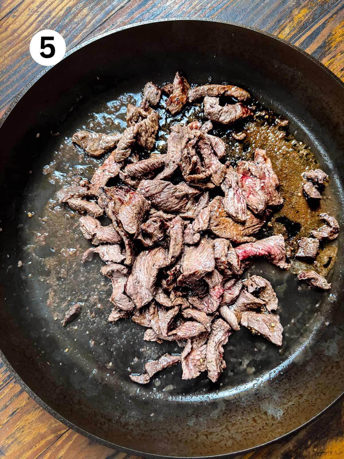 Browned venison stir fry meat in a cast iron pan.
