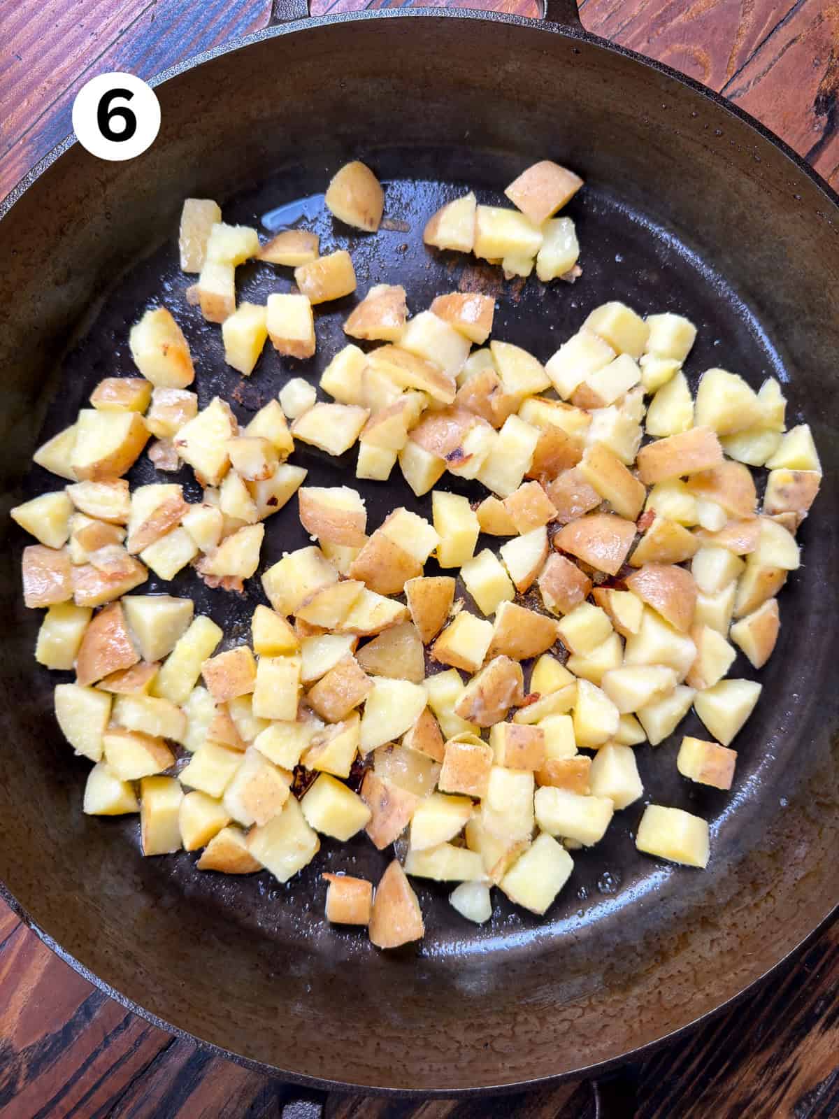 Diced potatoes cooking in a cast iron pan.