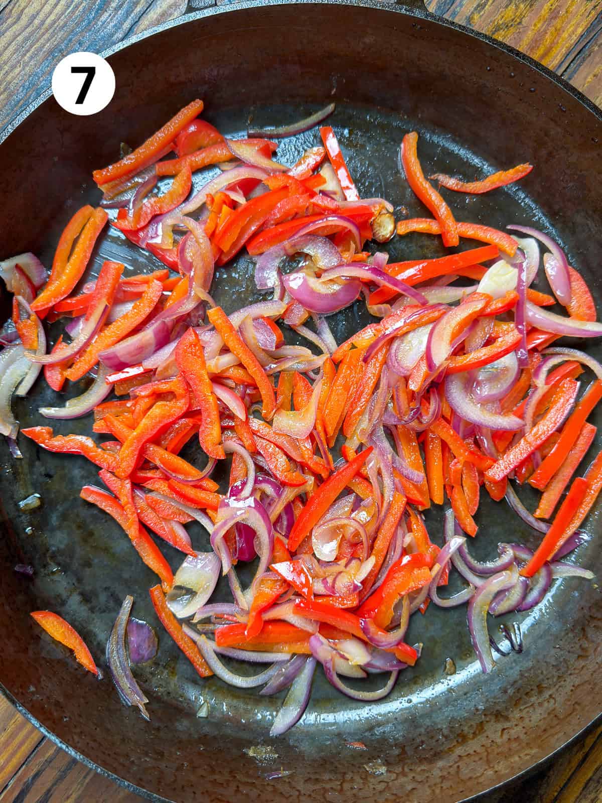 Onions and bell peppers in a cast iron pan.
