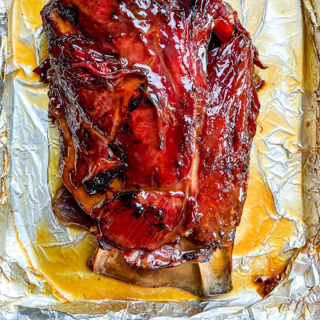 Glazed smoked venison roast pn a baking pan.