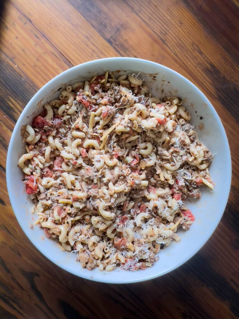 Ground venison, sauce, and pasta mixed in a bowl.