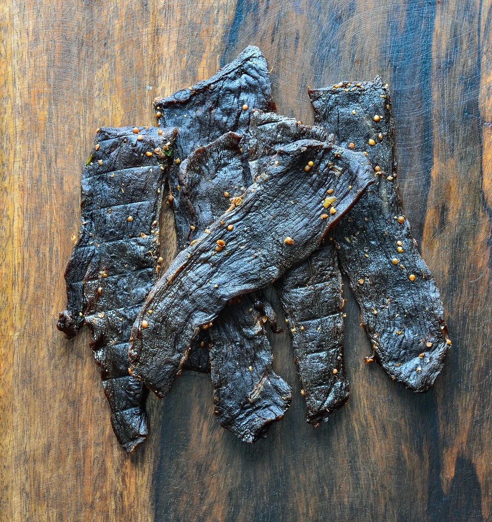 Dried venison jerky on a wooden cutting board.
