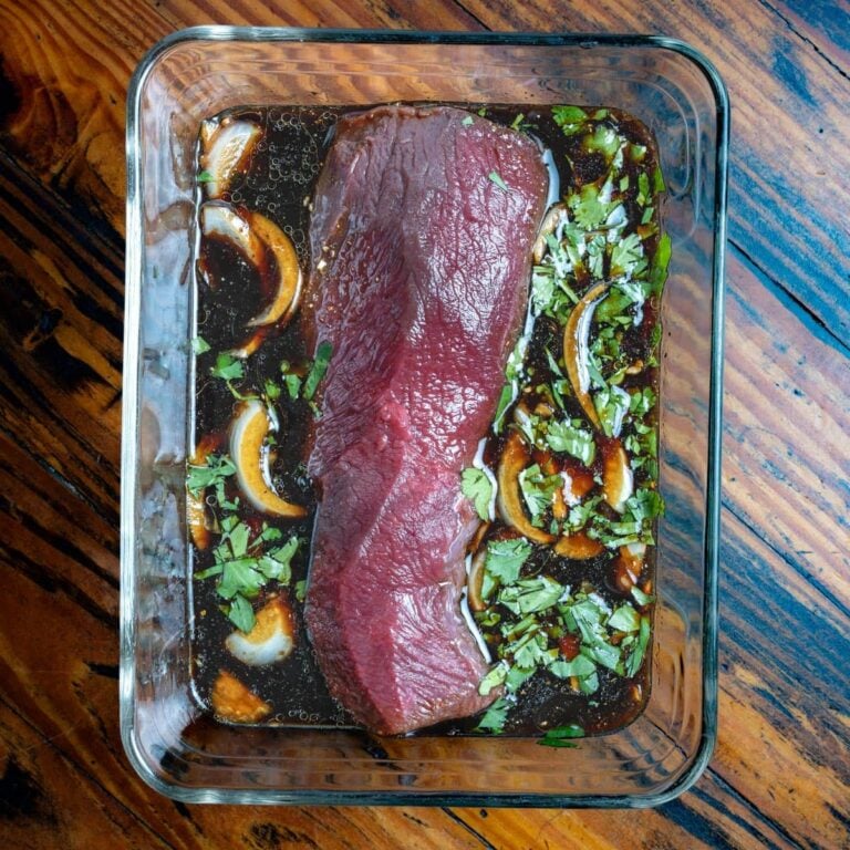 Venison marinating in a glass dish.