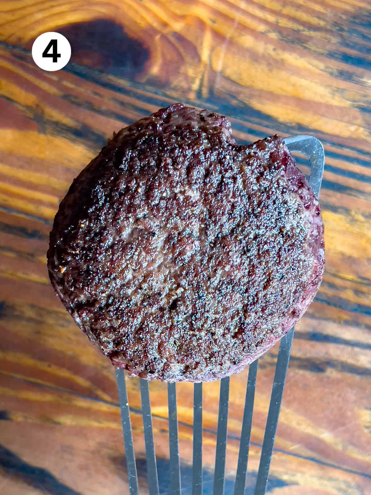 Cooked venison burger on a spatula.