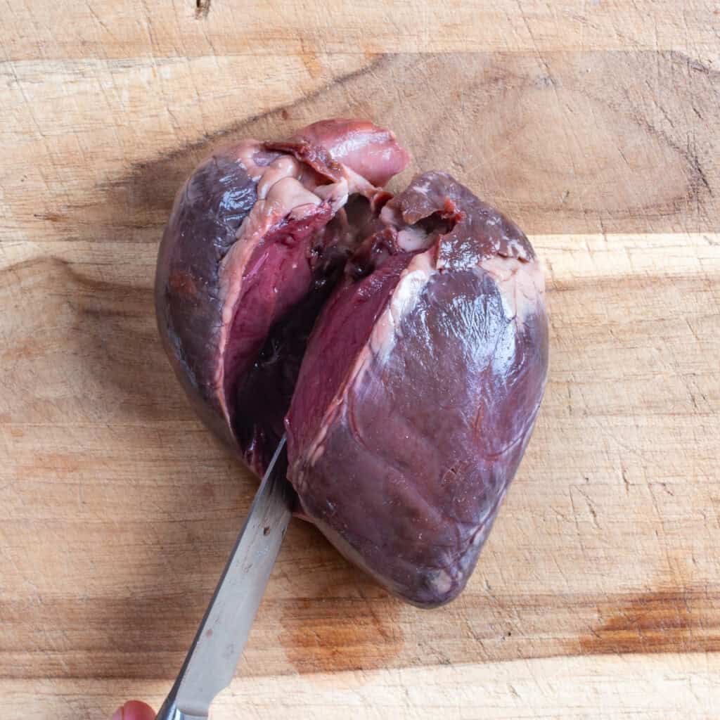 Slicing open a deer heart with a knife.