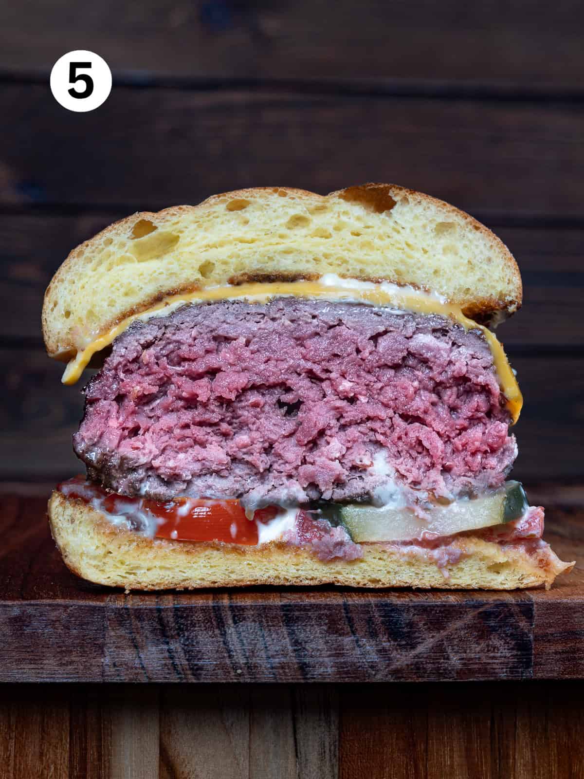 Venison burger cut in half on a wooden board.