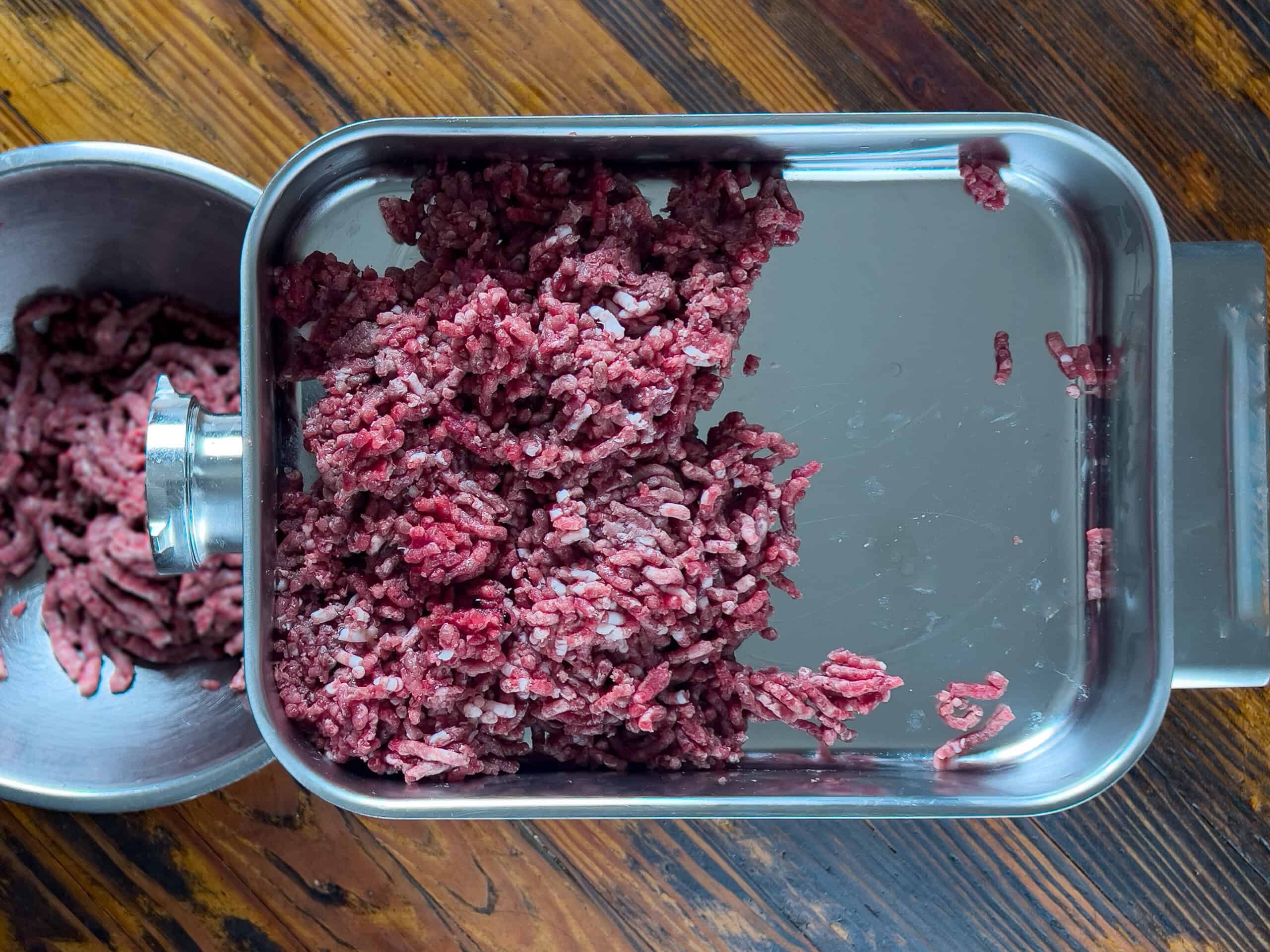 Ground venison resting in a grinder pan.