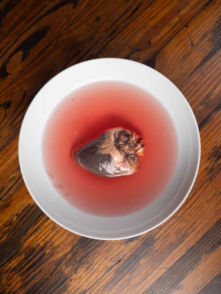 Rinsing a deer heart in a bowl of water.