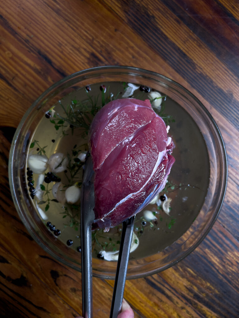 Placing the deer roast in the brine.