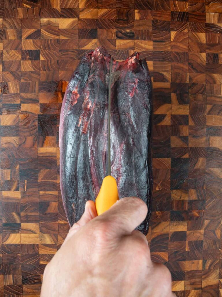 cutting into a venison neck with a boning knife.