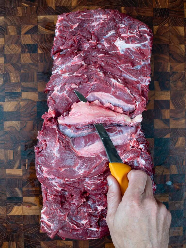 Removing the nuchal ligament from the meat.