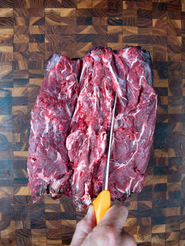 Cutting down each side of the deer's neck and spine
