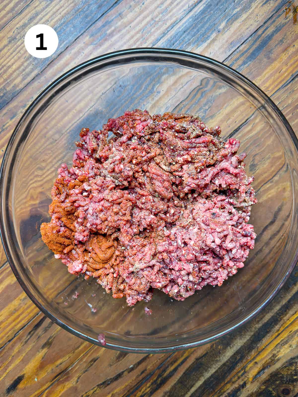 Ground venison in a bowl with chili spices.