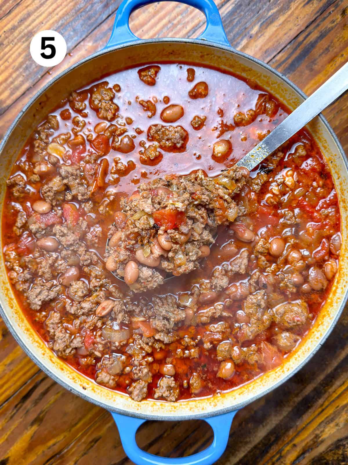 Venison chili with beans in a pot with a silver serving spoon.