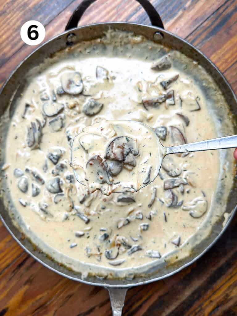 Venison stroganoff sauce in a pan with a silver serving spoon.