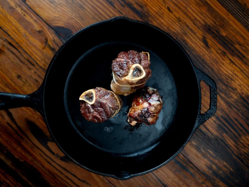 seared venison shanks in cast iron pan.