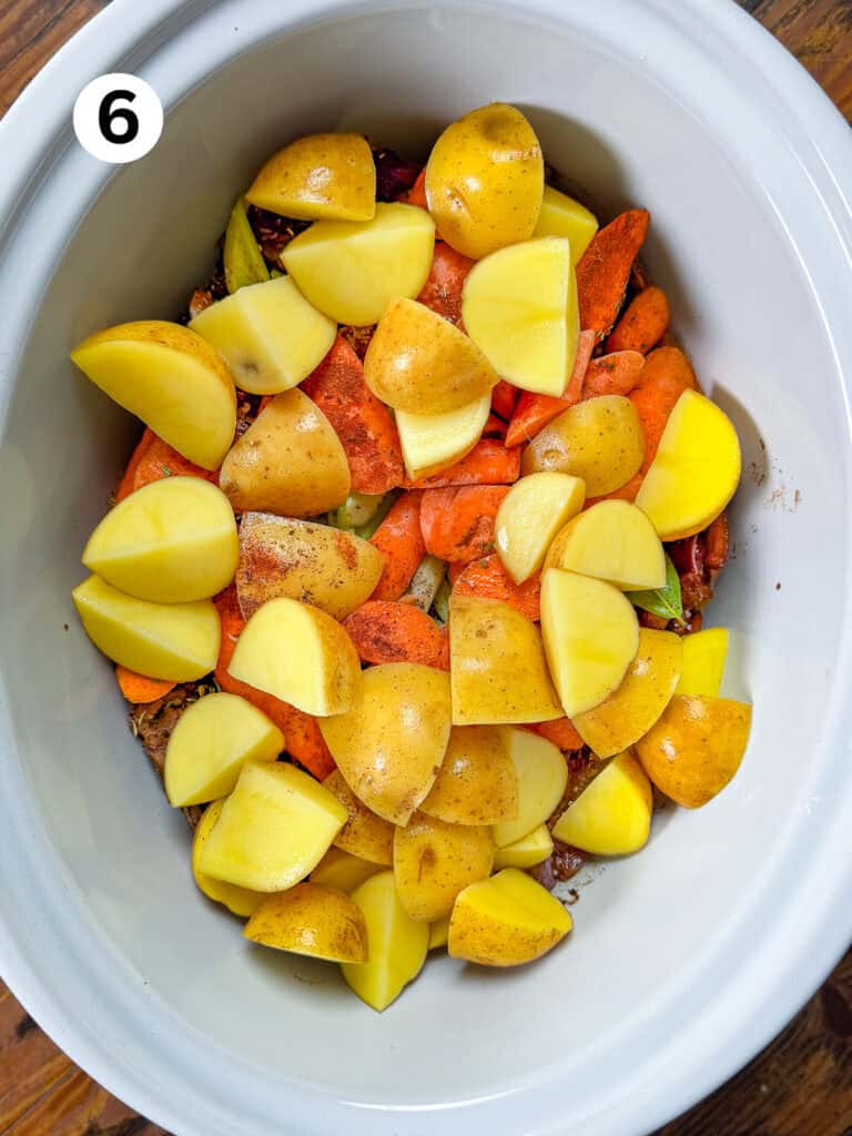 Carrots and potatoes in a white slow cooker.