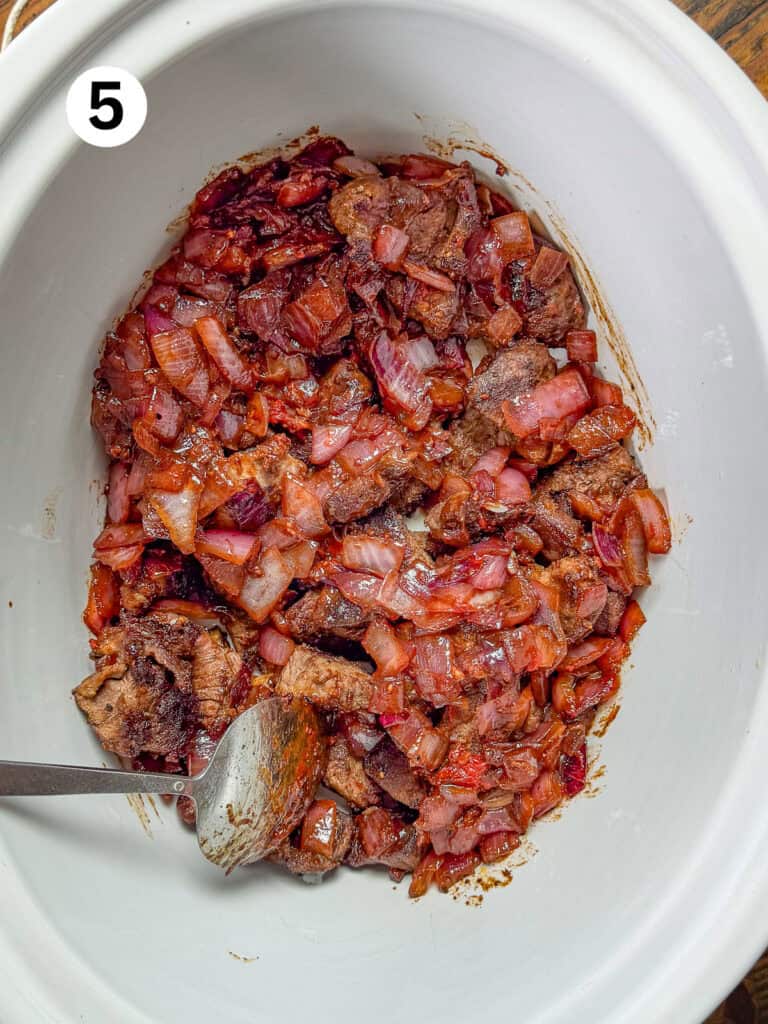 Deglazed venison with onions, garlic and carrots in a slow cooker.