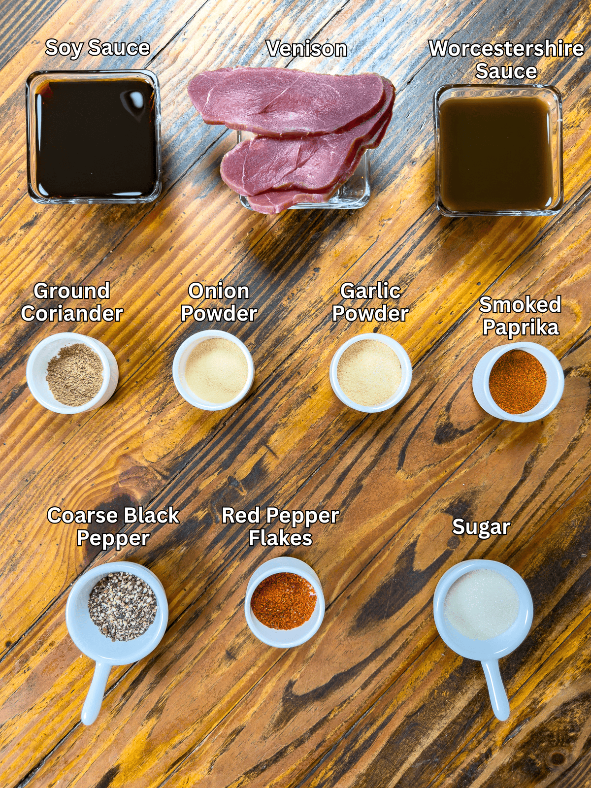 Ingredients for smoked venison jerky on a wooden table.