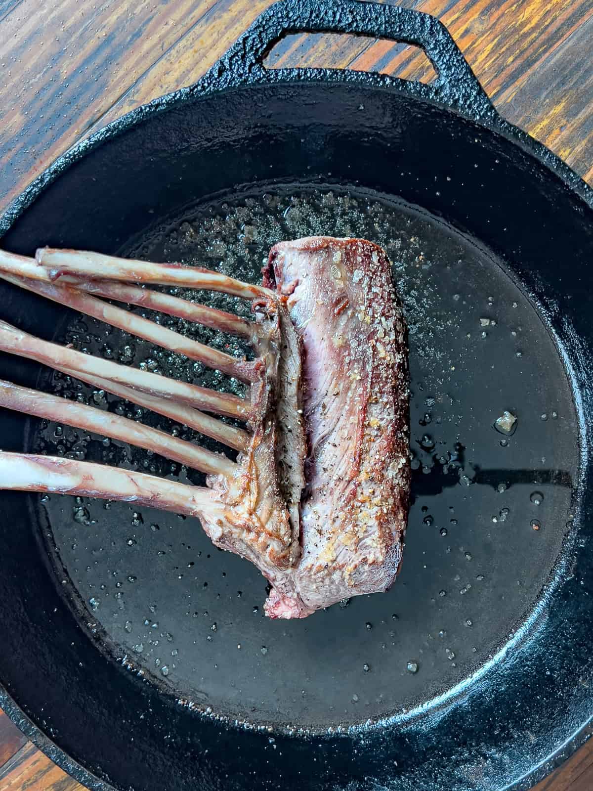 Seared rack of venison in a cast-iron pan.