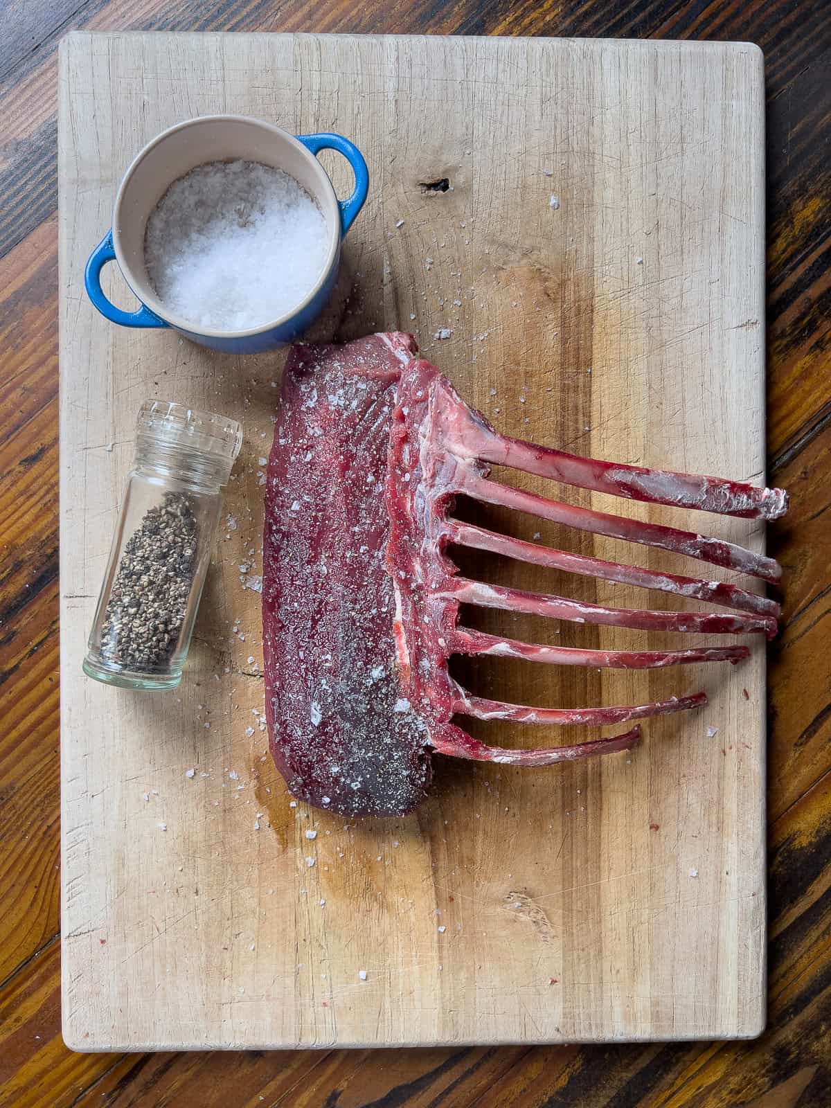 Seasoned rack of venison on cutting board.