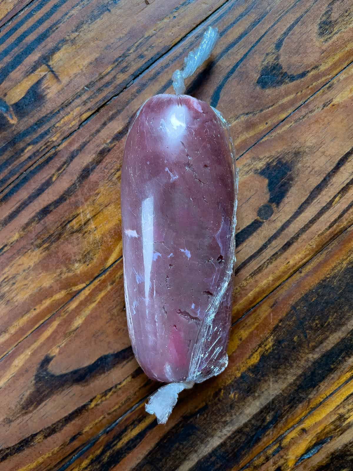 Venison loin rolled and tied in plastic wrap.