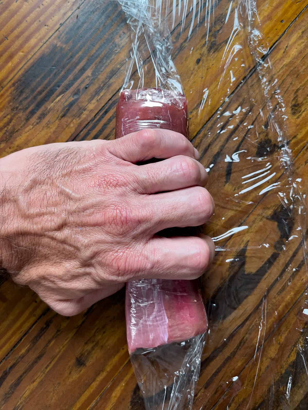 Rolling venison loin in plastic wrap.
