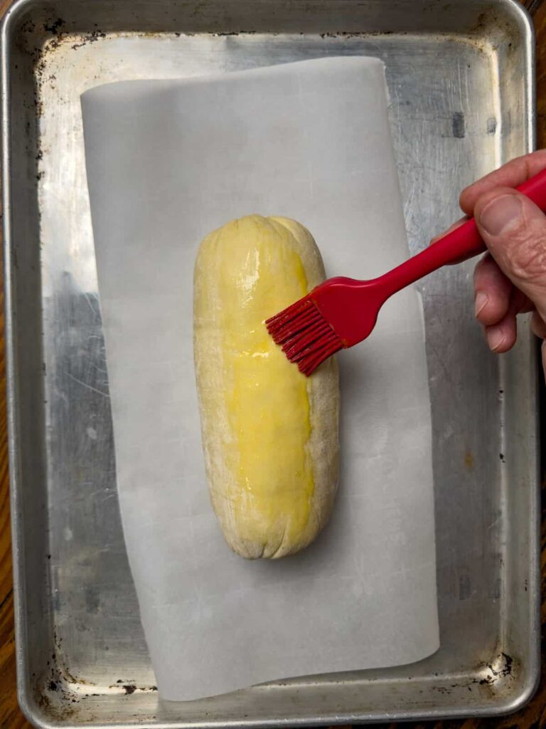 brushing a venison wellington with egg yolk.