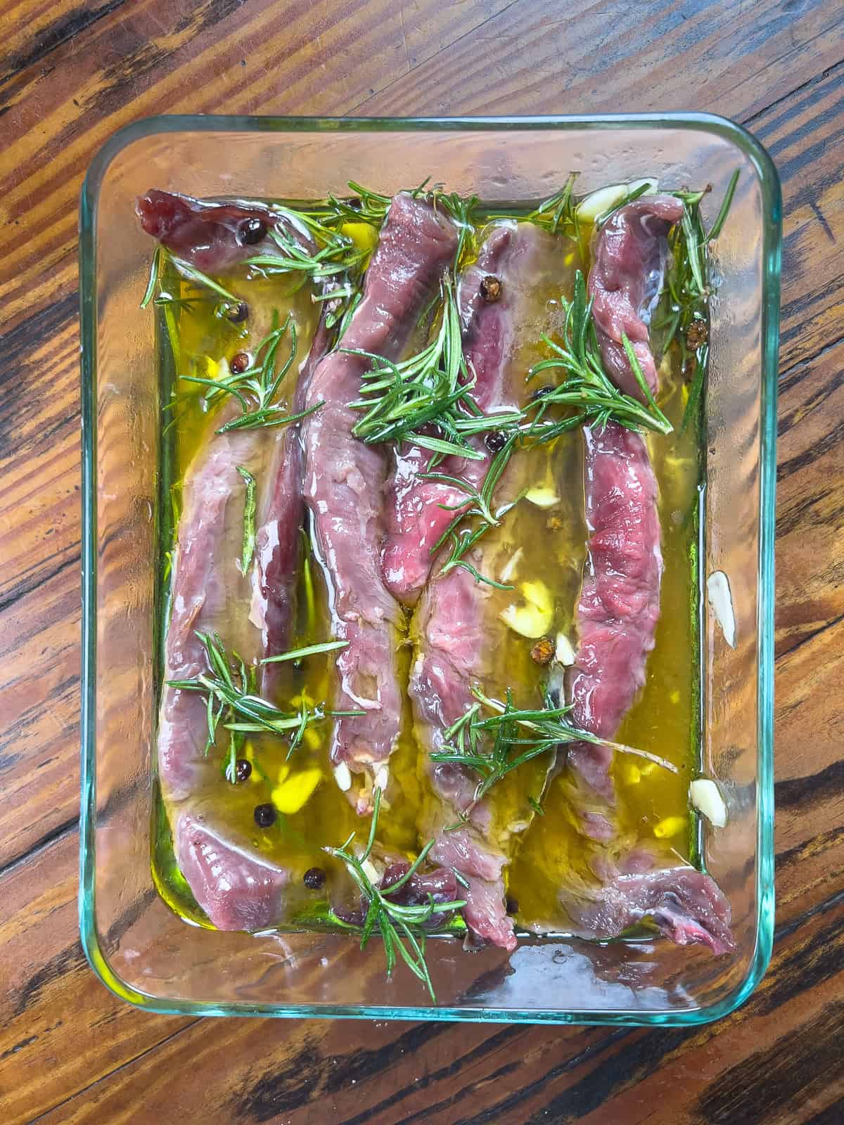 Venison tenderloins marinating in a glass dish.