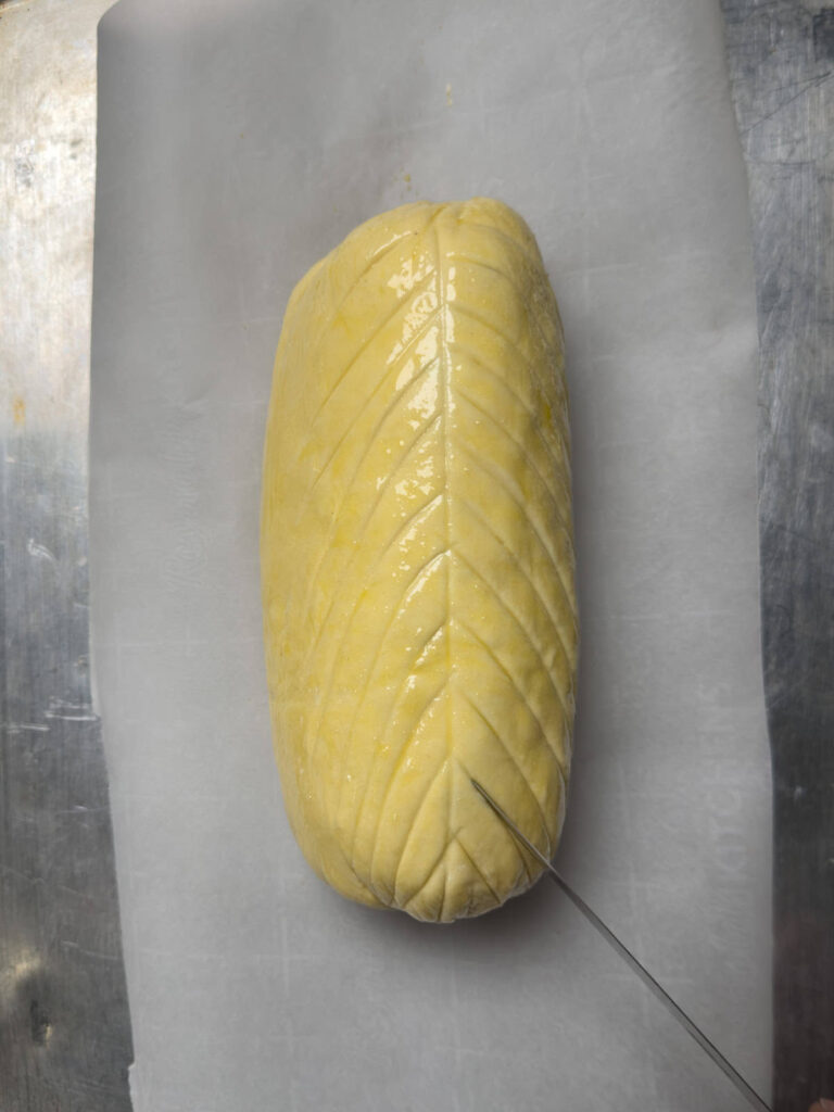 scoring a venison wellington with a knife.