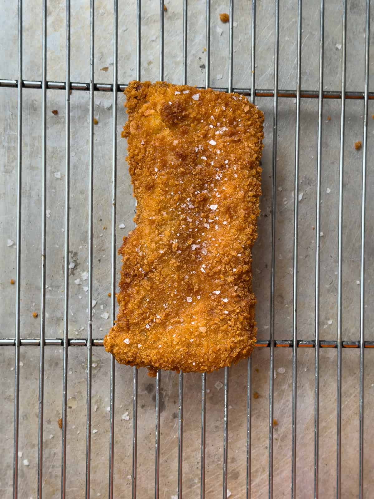 Pork tonkatsu resting on a wire rack.