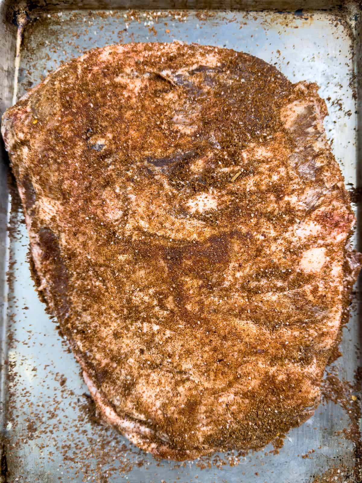 Uncooked, seasoned wild boar ribs on a pan.