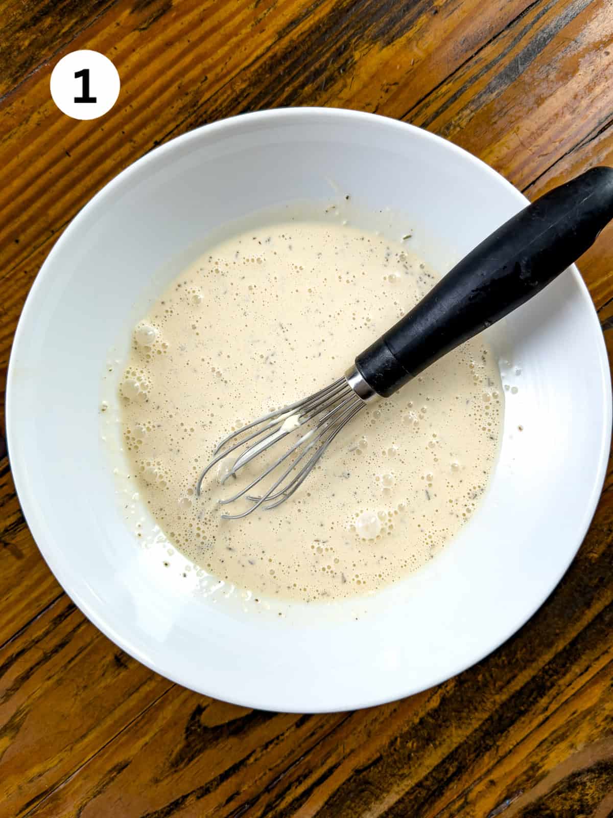 Alabama white sauce mixed with a whisk in a bowl.