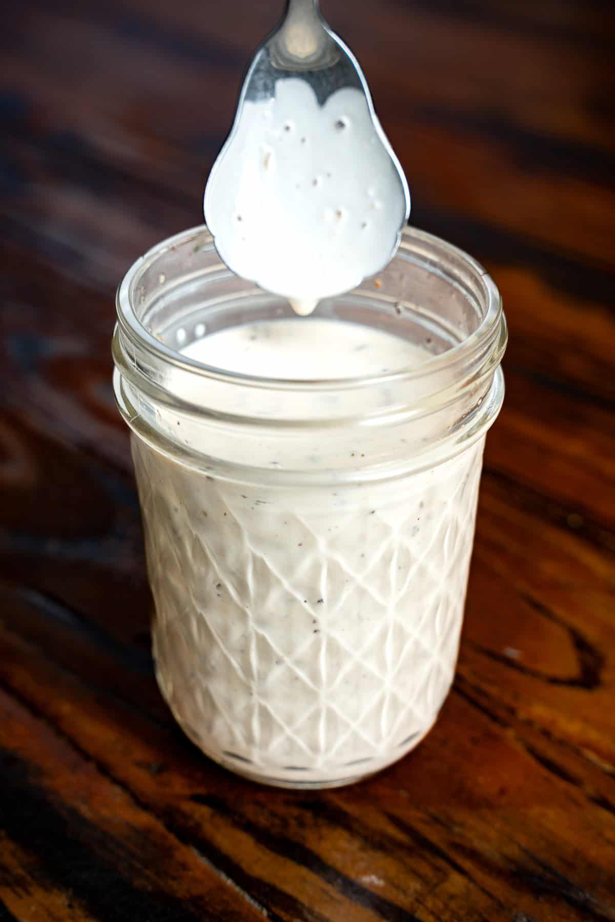 Alabama white sauce in a mason jar with a spoon.